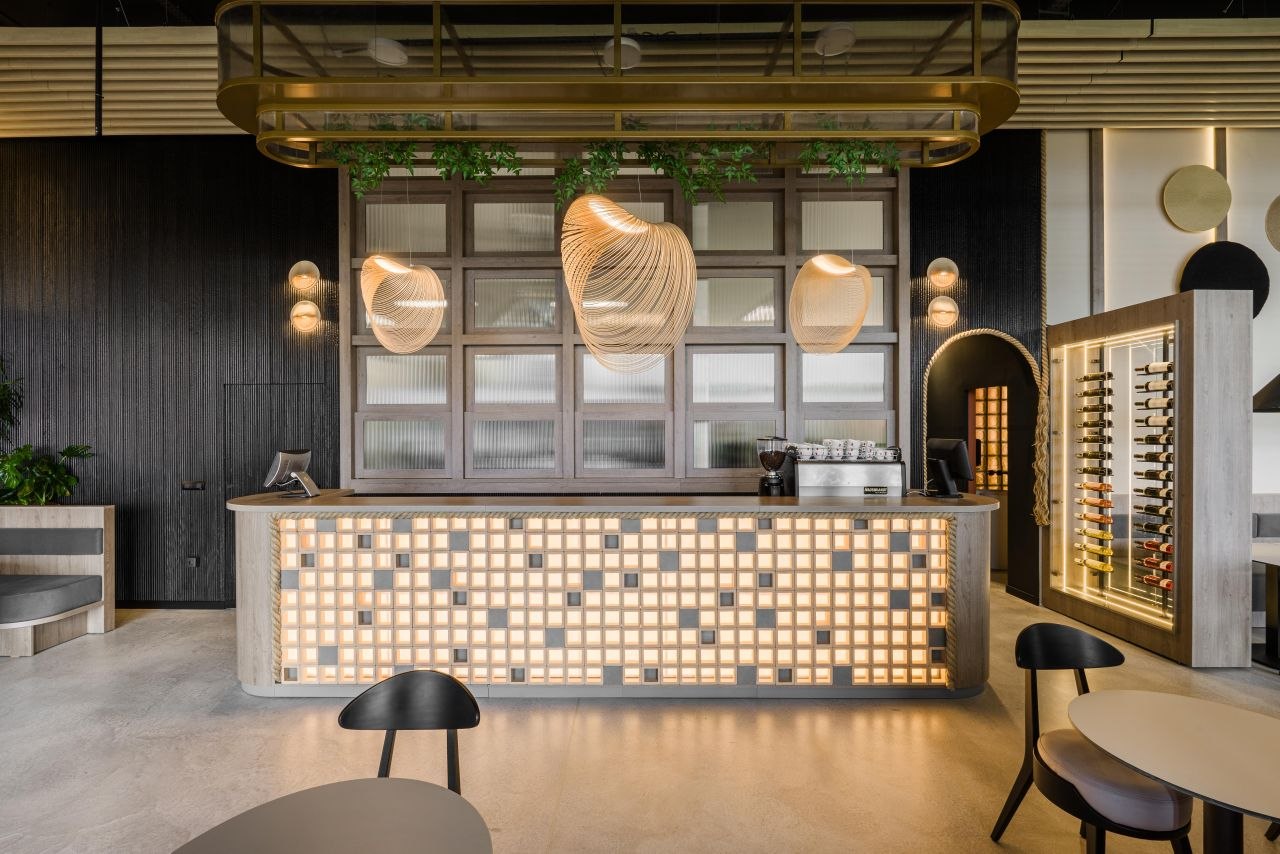 The Wok hospitality interior with warm timber, dark ribbed surfaces, softly lit counter and large woven pendants