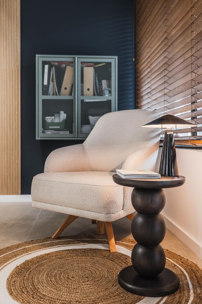 Adrett — a waiting corner with textured upholstery, wood and filtered light, where matte materials and subtle accents prevent a sterile salon feel.